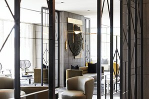 A modern interior with a sectional sofa, a coffee table, and a decorative wall piece. - AC Hotel by Marriott Miami Airport West/Doral (Miami)