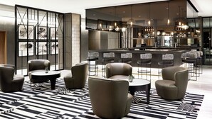 A modern lounge area with leather sofas, a bar with stools, and a patterned rug.