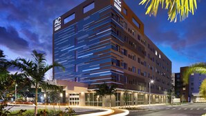 A modern hotel with a prominent AC logo, multiple floors, and a well-lit facade.