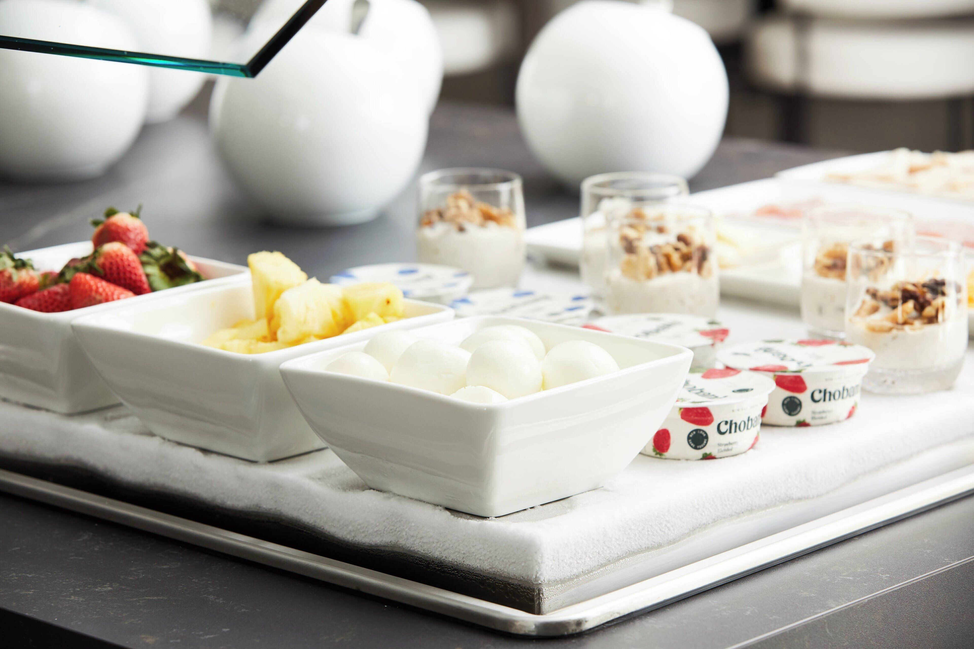 Un bufé de desayuno con diversas opciones de comida, incluyendo frutas, yogur y granola.