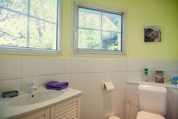 A bathroom with a white sink, a toilet, and a window with blinds.
