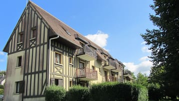 Un bâtiment traditionnel à colombages, doté de plusieurs balcons et d’une pelouse bien entretenue.