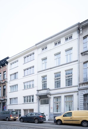 A multi-story building with a white facade, several windows, and a door. - Saint Pauls Suite 1 (Antwerp)
