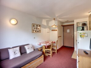 A compact living space with a sofa, a small dining table, and a kitchenette.