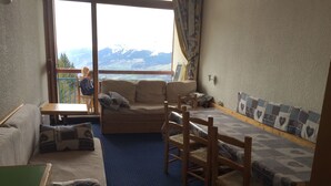 Ein gemütlicher Raum mit einer Couch, einem kleinen Tisch und einem Bett mit gemustertem Überwurf.