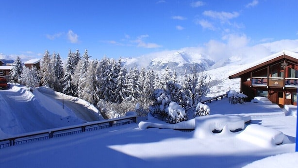 Ein schneebedecktes Bergresort mit Holzhäusern und blauem Himmel.