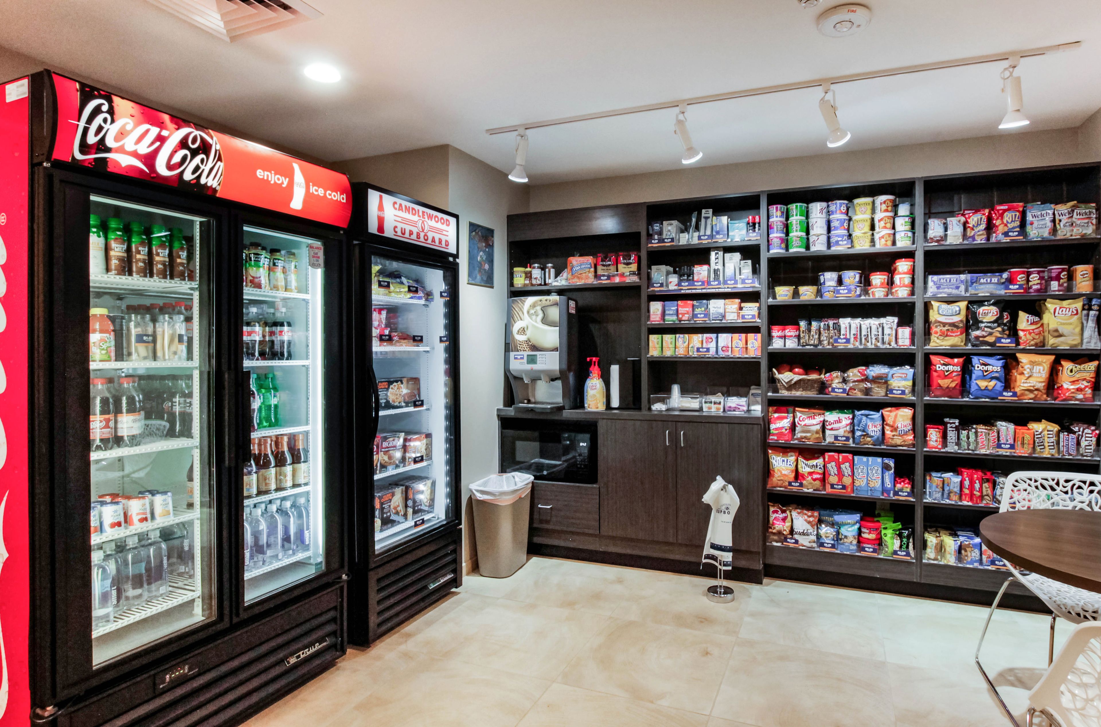 Een snackbar met Coca-Cola koelkasten, schappen vol snacks en een prullenbak.