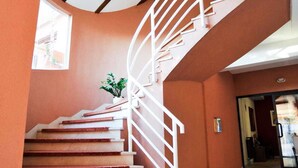 Una escalera de caracol con barandillas blancas y escalones de madera, que lleva a un piso superior.