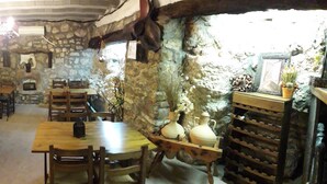 A rustic dining area with stone walls, wooden tables and chairs, and a chandelier. - Albergue Rural Cal Picarol (Camarasa)