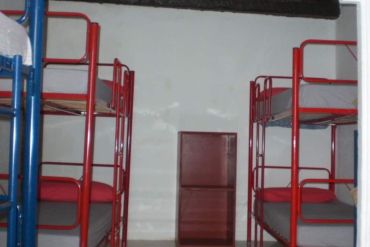 A dormitory room with bunk beds, a small cabinet, and a tiled floor.