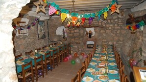 A long dining table set with chairs, surrounded by stone walls and decorated with colorful balloons and star-shaped ornaments. - Albergue Rural Cal Picarol (Camarasa)