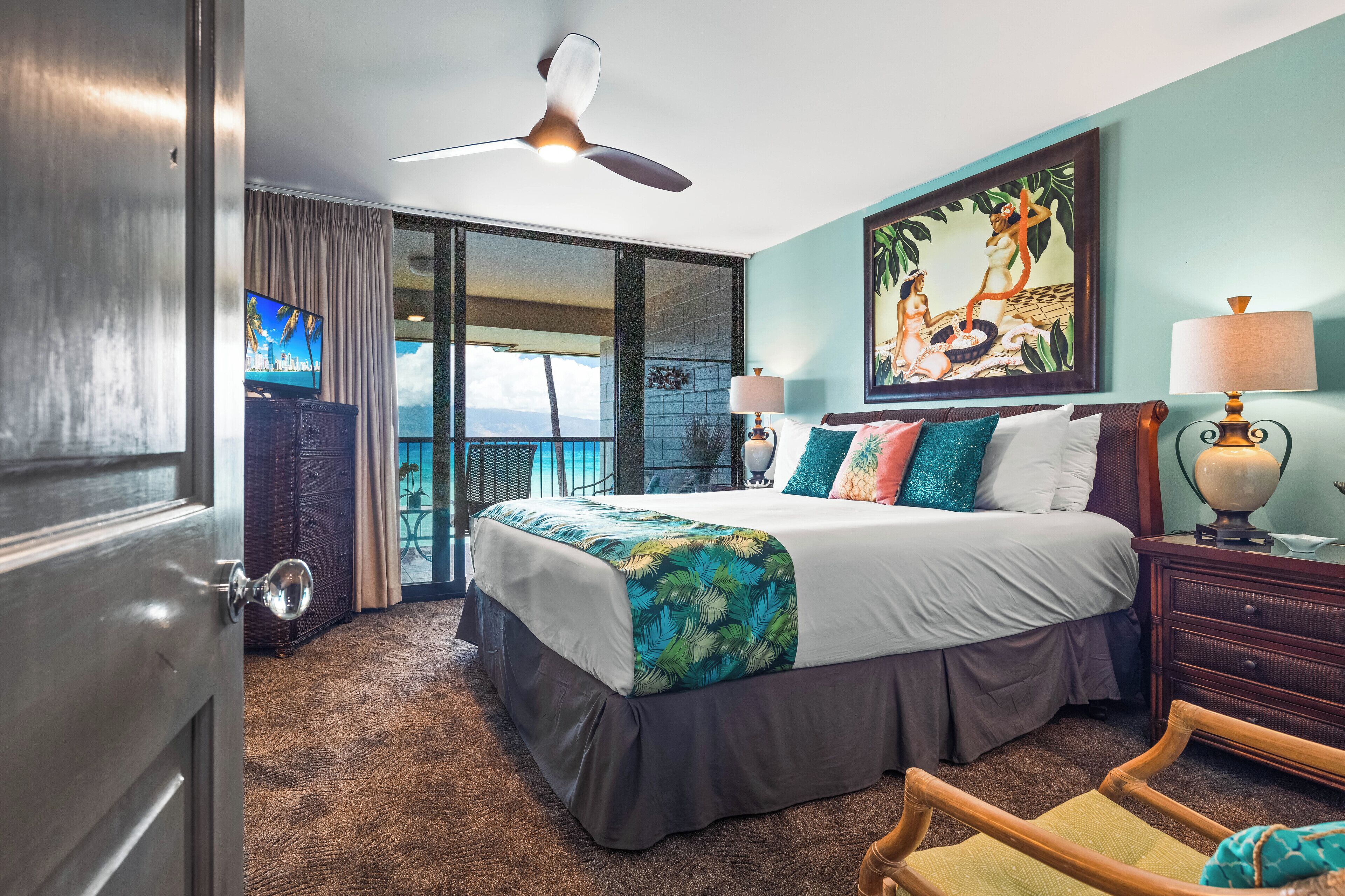 A hotel room with a bed, a television, a balcony with a view, and a painting on the wall.