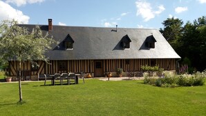 A traditional half-timbered building with a sloped roof, a front porch, and a well-maintained lawn.