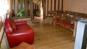 A rustic interior with a wooden dining area, a red leather sofa, and a small table.