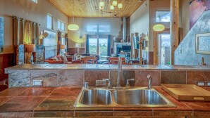 A spacious living area with a large fireplace, a stone countertop with a sink, and a view of the outdoors. - Amazing Views, Hot Tub, Pool, Sauna, Gourmet Kitchen, Master Suites!  (Santa Fe)
