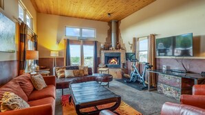 A cozy living room with a fireplace, leather furniture, and a television. - Amazing Views, Hot Tub, Pool, Sauna, Gourmet Kitchen, Master Suites!  (Santa Fe)