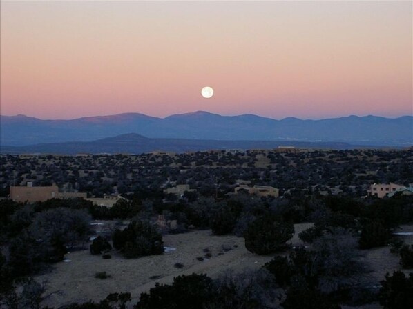 A landscape with a large moon in the sky, mountains in the background, and a town below.