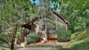 A cabin with a wooden exterior, a porch, and a small garden area. - Lovesong #9- Charming & Clean Log Cabin!! (Sevierville)