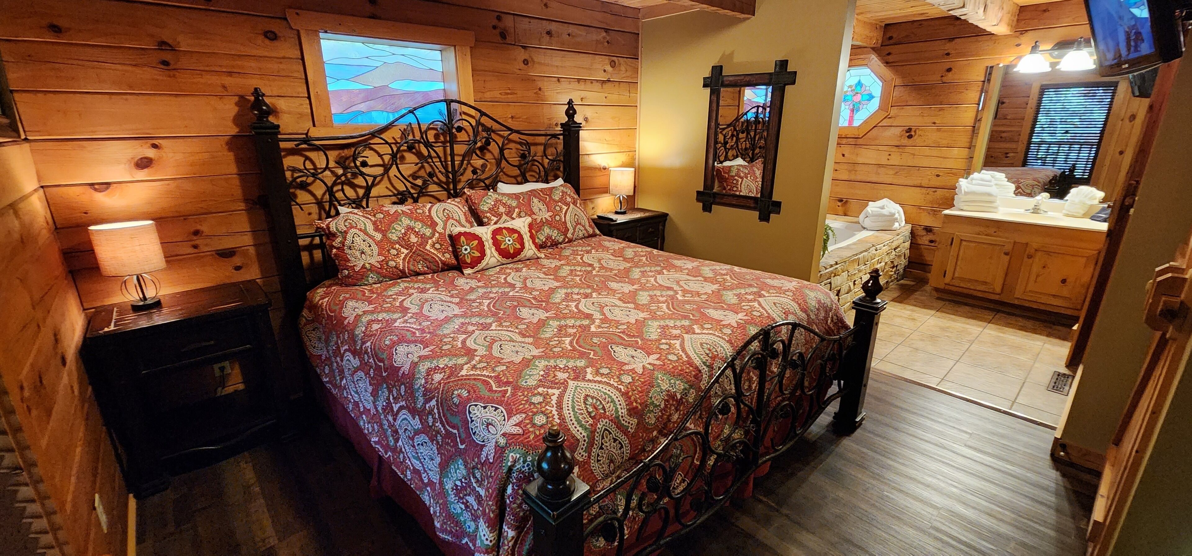 Une chambre à coucher de style cabane en bois, comprenant un lit, des tables de chevet, une commode et un téléviseur.