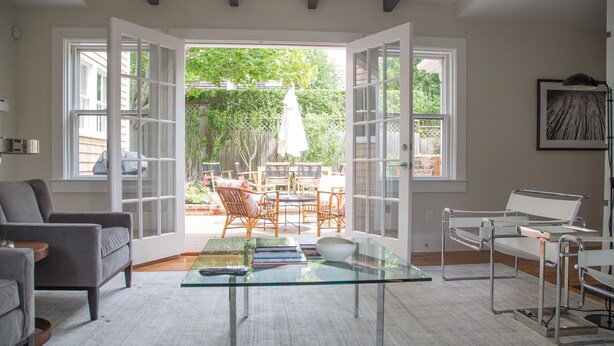 An open-plan living area with a glass coffee table, seating arrangements, and a view of the backyard. - Luxurious 5 bedroom home with hot tub and pool in prime location (Nantucket)