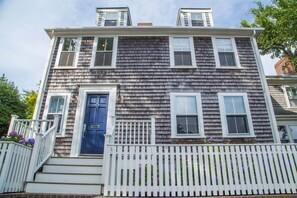 A two-story house with a dark shingled exterior, white trim, and a blue front door.