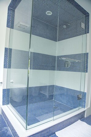 A glass-enclosed shower with a blue mosaic tile design.