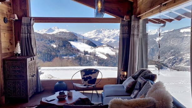 Una habitación acogedora con un ventanal que ofrece vistas a montañas nevadas.