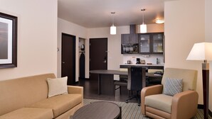 A compact living space with a sofa, armchair, coffee table, kitchenette, and a dining area.