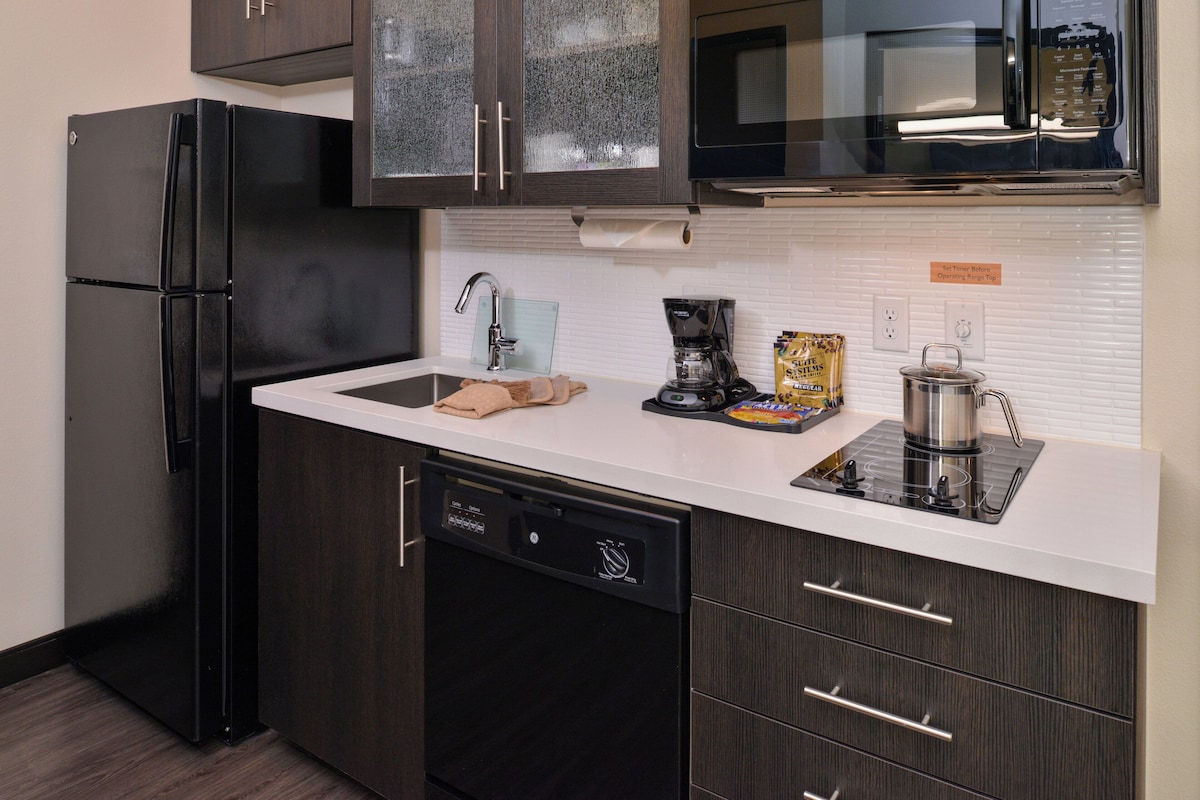 A modern kitchen with a black refrigerator, a coffee maker, and a kettle on the counter.