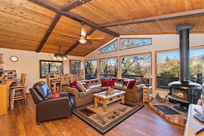 Un acogedor interior de cabaña con chimenea, muebles de madera y ventanas amplias.