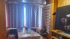 A cozy cabin interior with a wooden table set for two, a television, and a bench. - Tignes Grand Appartement 10p Exceptional View Pied Des Pistes (Tignes)