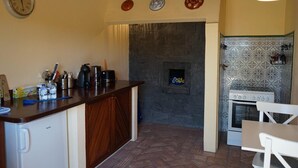 A compact kitchen with a built-in stove, a coffee maker, and a small refrigerator.