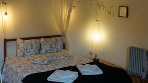 A bedroom with a bed, bedside lamps, a radiator, and a ceiling fan.