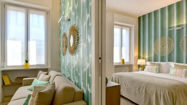A hotel room with a bed, a sofa, and a large window.