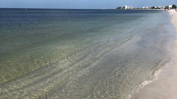 Une plage avec une eau claire et peu profonde et un rivage sablonneux.