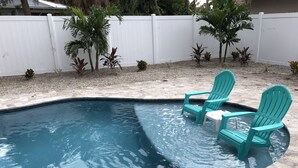 Une piscine avec deux chaises turquoise et une petite table.