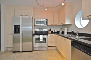 Enjoy cooking in this well-equipped kitchen with a refrigerator, microwave, and oven, along with ample counter space and a convenient sink area.