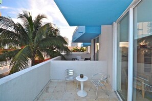 Relax and dine on this balcony with a table and two chairs, surrounded by a large palm tree.