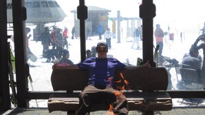 A person sitting on a bench with a fire in front of them.