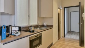 Et moderne køkken med indbygget ovn, vask og en bordplade med diverse hårde hvidevarer.