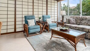 A living room with a traditional Japanese shoji screen, two blue armchairs with patterned cushions, a wooden coffee table, and a patterned sofa.