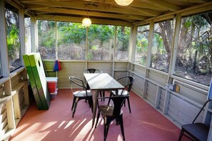 Una veranda coperta con tavolo e sedie, circondata da finestre che offrono vista sul paesaggio.