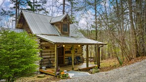 A rustic cabin with a porch, wooden deck, and a small garden area.