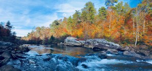 A river flowing through a forest with autumn foliage.