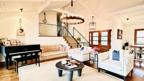 Ein großzügiger Wohnraum mit Flügel, einer Treppe und einer Chandelier.