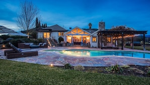 Ein Haus mit Swimmingpool, Sitzgelegenheiten im Freien und einer überdachten Terrasse.