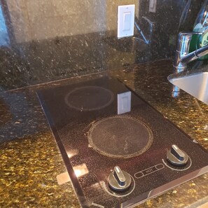 Una cucina con piano di lavoro in granito nero, fornello in acciaio inossidabile e una bottiglia verde di detersivo per piatti.