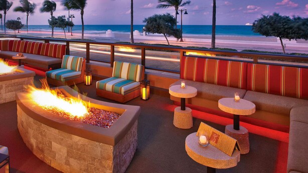 Eine Strandbar mit Feuerstellen, bequemen Sitzgelegenheiten und kleinen Tischen.