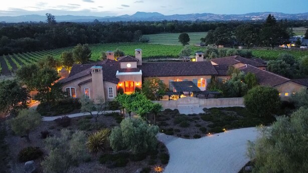 Il s’agit d’un vaste domaine comprenant plusieurs bâtiments, dont une maison principale avec un toit en tuiles et plusieurs dépendances plus petites. De beaux jardins et des vignobles bien entretenus entourent la propriété.