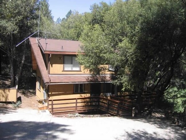 A two-story house with a sloped roof, surrounded by dense trees. - Secluded, Romantic Getaway. Perfect for Families Too! (Pine Mountain Club)